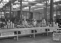 854201 Interieur van de hoofdwerkplaats van de N.S. te Amersfoort, met enkele arbeiders aan een werkbank met lagers.